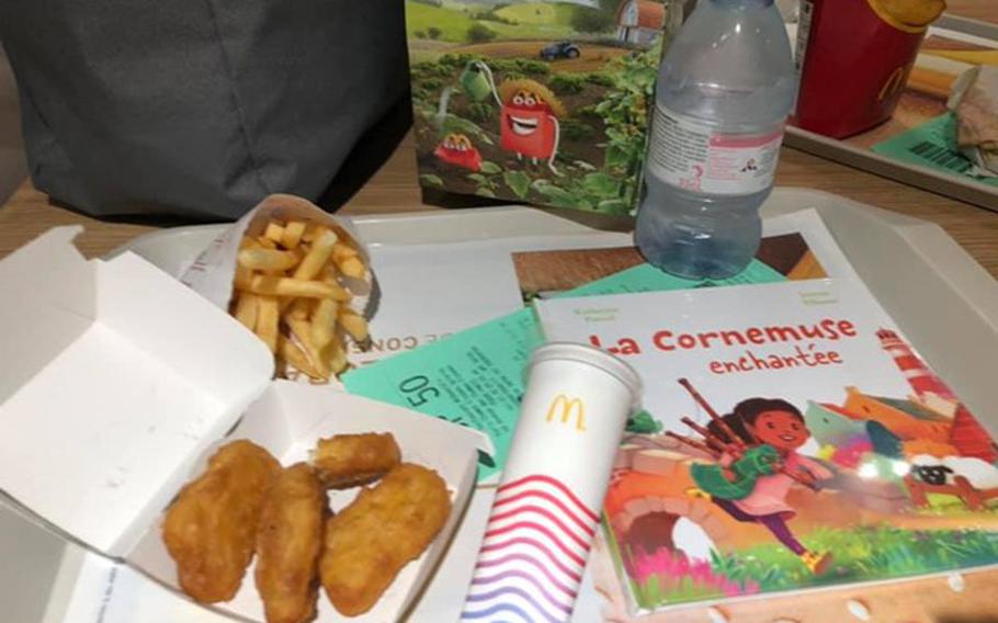 Happy meal on a tray with an open box of four McNuggets®, a small books, a small bag of French fries and a frozen McDonald’s popsicle. 